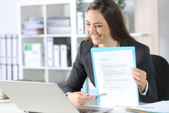 woman holding letter up to her laptop screen